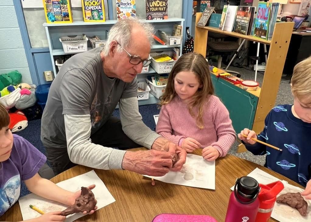 Facilitator helping a student sculpt the American Red Wolf in clay