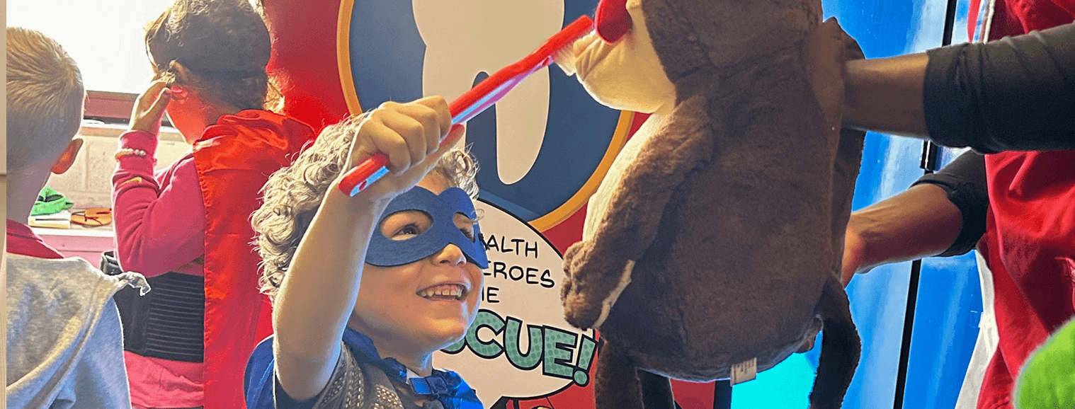 young boy with superhero mask and practicing brushing teeth