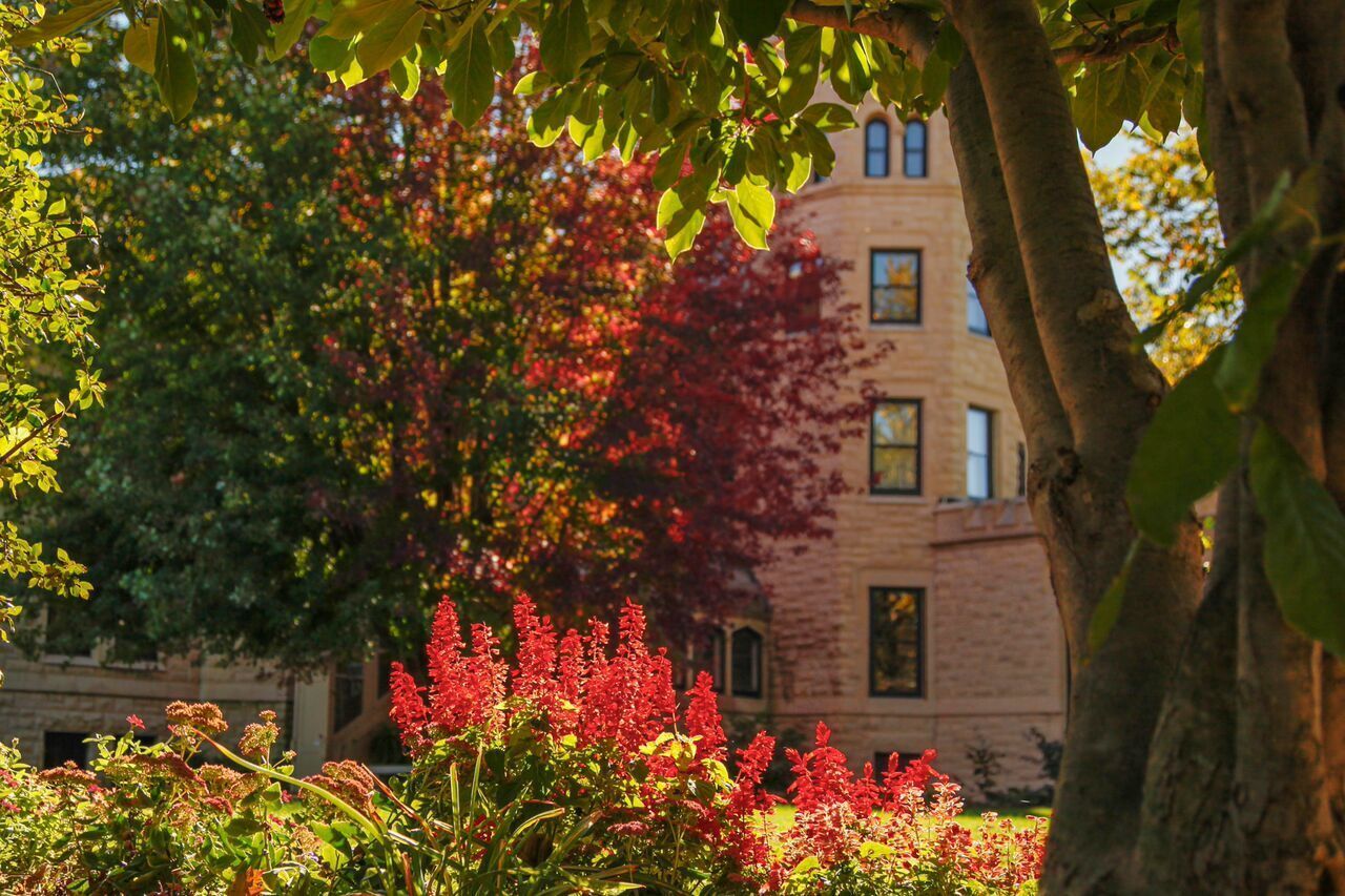 A stone castle in the background of fall plants in red and burgundy hues.