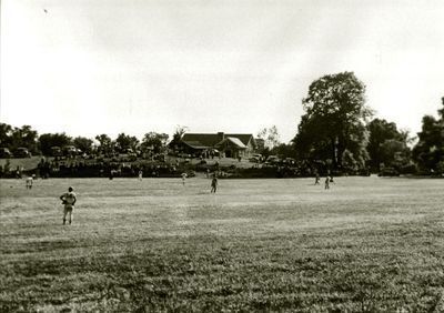 An open field at Charlton Park with the Museum in the background and a baseball team playing in the foreground.