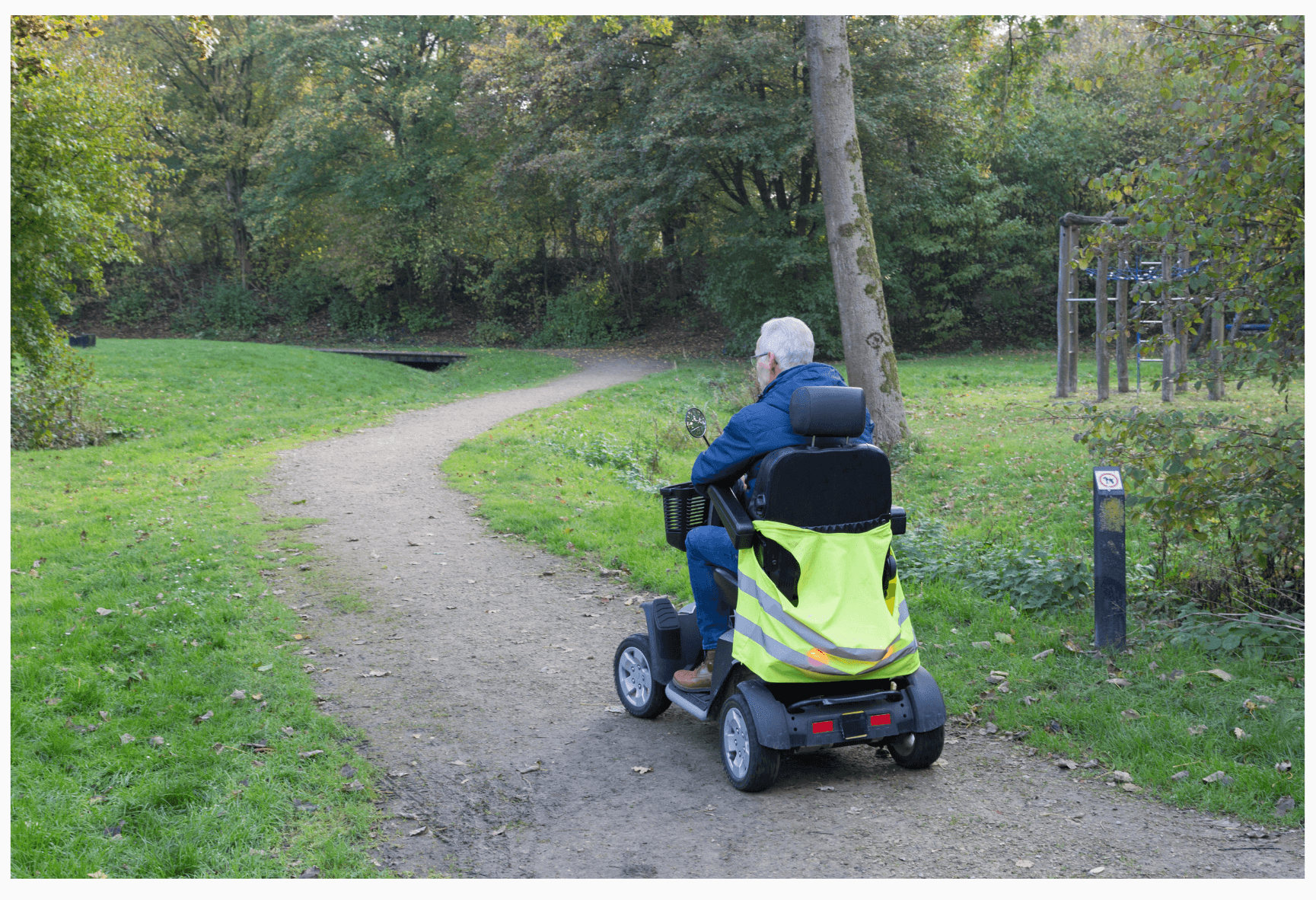 Guy on mobility scooter going down a dirt path in the park