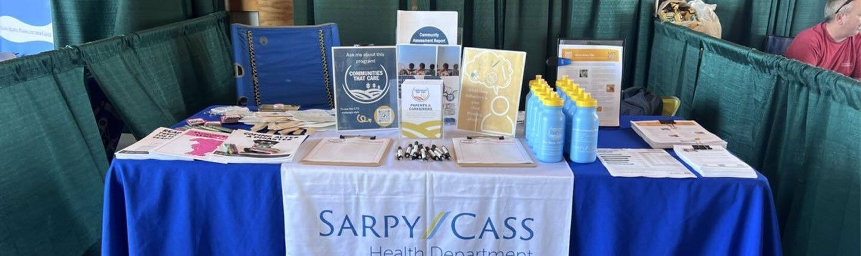 Photo of a table of promotional materials plus the Sarpy/Cass Health Department logo tablecloth