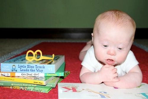 Child with Down syndrome looking through a book.