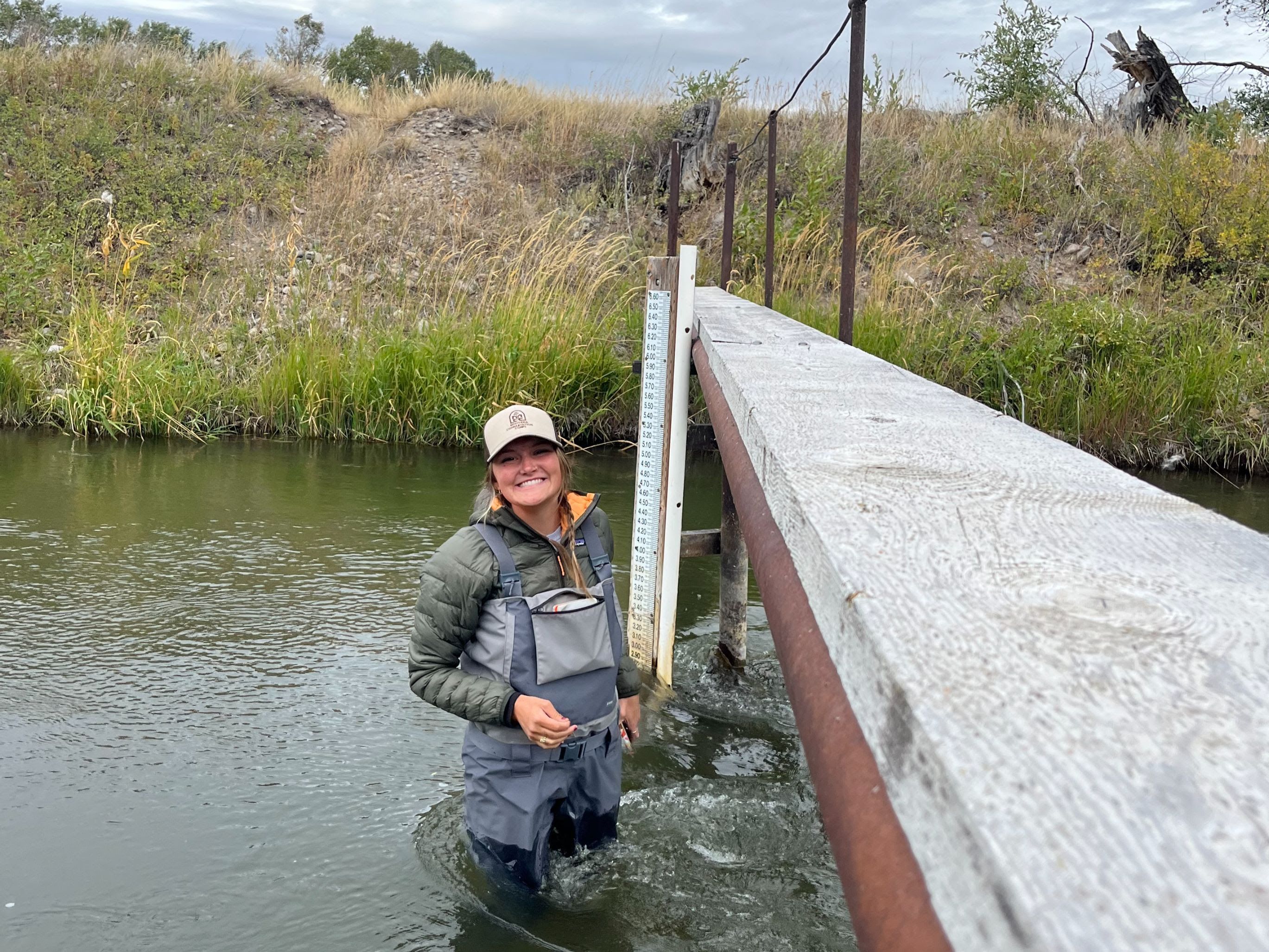 Megan wades in a river to take flow rate samples