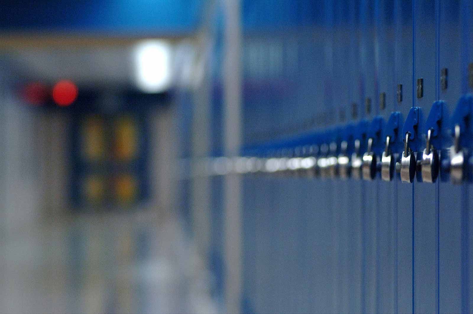 Blue lockers in an empty school hallway.