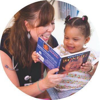 Clinician and young girl read book together