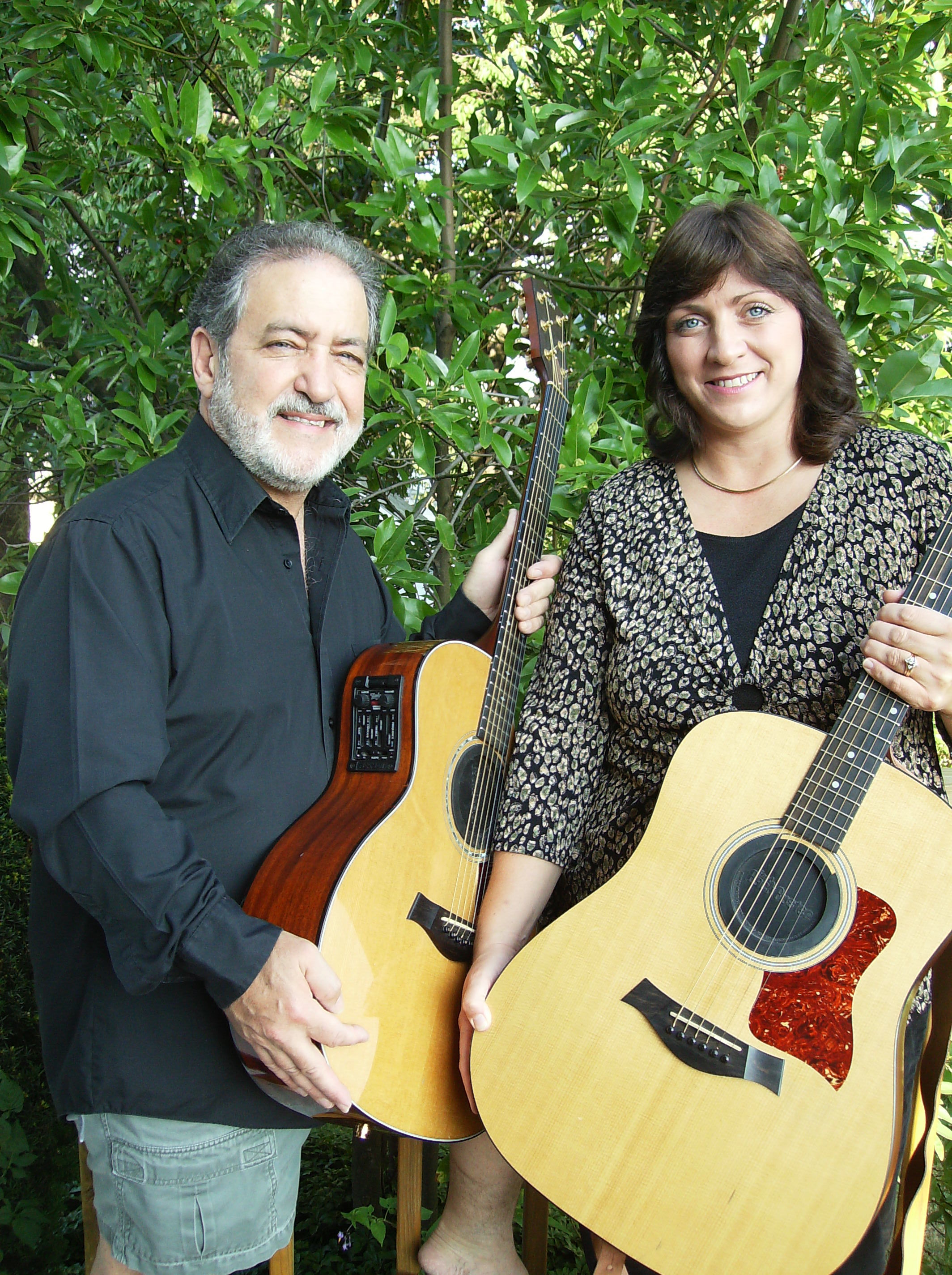 A man and woman posing with acoustic guitars