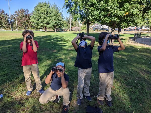 Paul Cuffee Elementary School look through their binoculars in the field at Neutaconkanut Hill Park