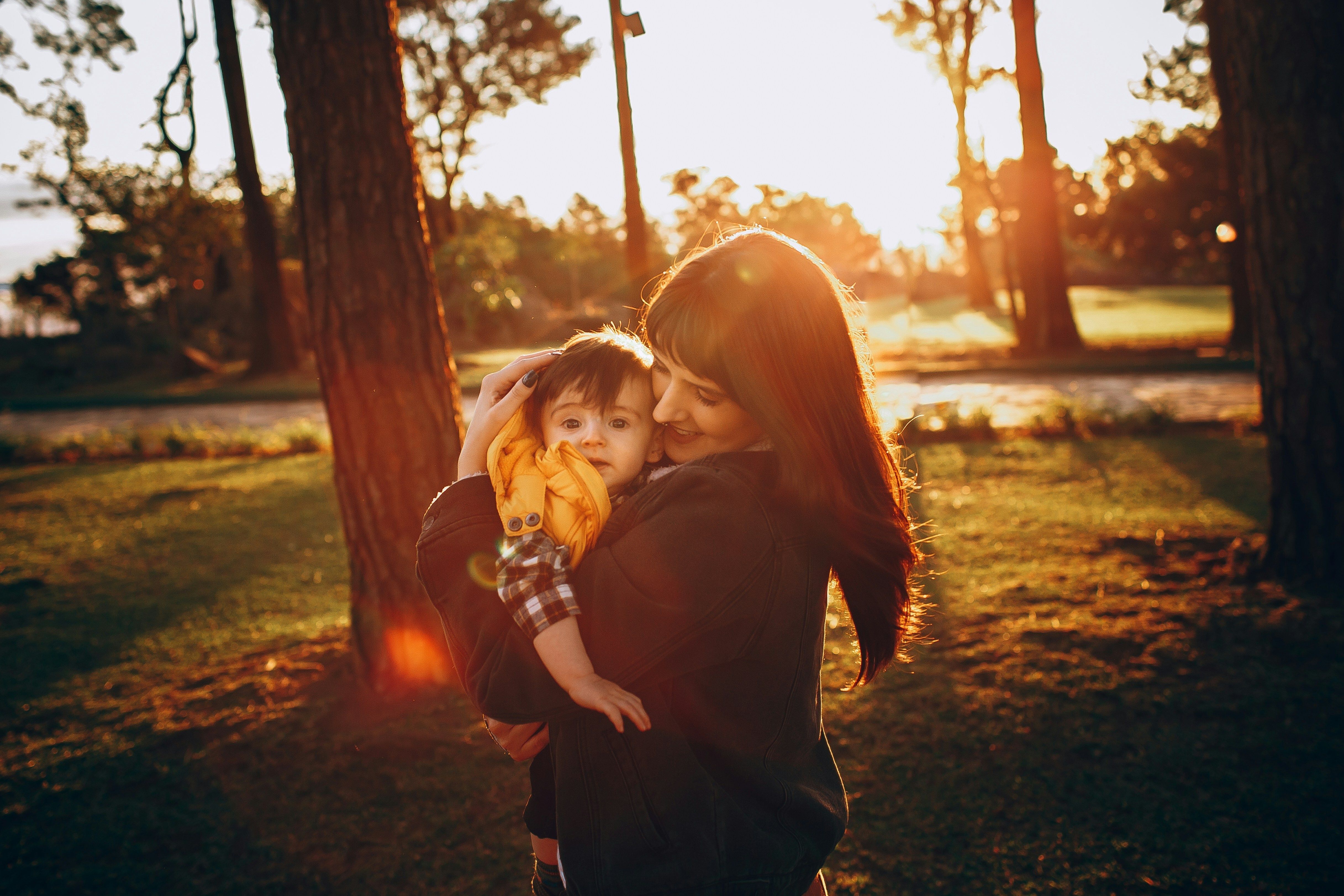 mother holding child outside on sunny day