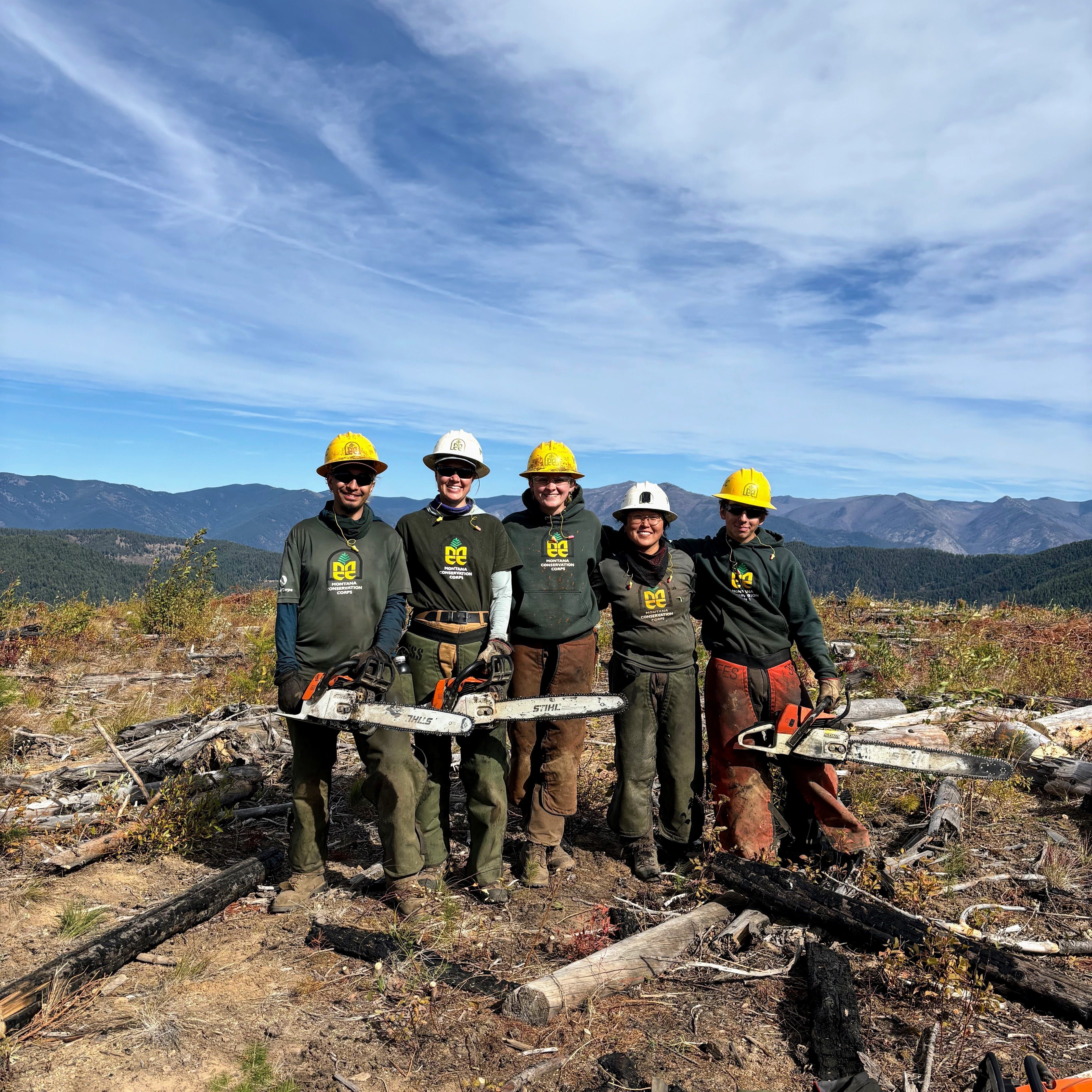 A crew stands at an overlook, smiling at the camera