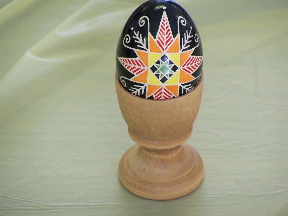 Egg shell ornately decorated with geometric patters in black, yellow, and orange colors.