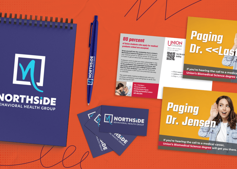 A spiral bound notebook with a logo for Northside Behavioral Health Group on it, alongside business cards and a pen with the same logo. A direct mailer example for Union College. 