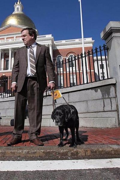 Carl Richardson in front of the Massachusetts State House with guide dog Kinley
