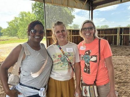 three women standing in a horse barn