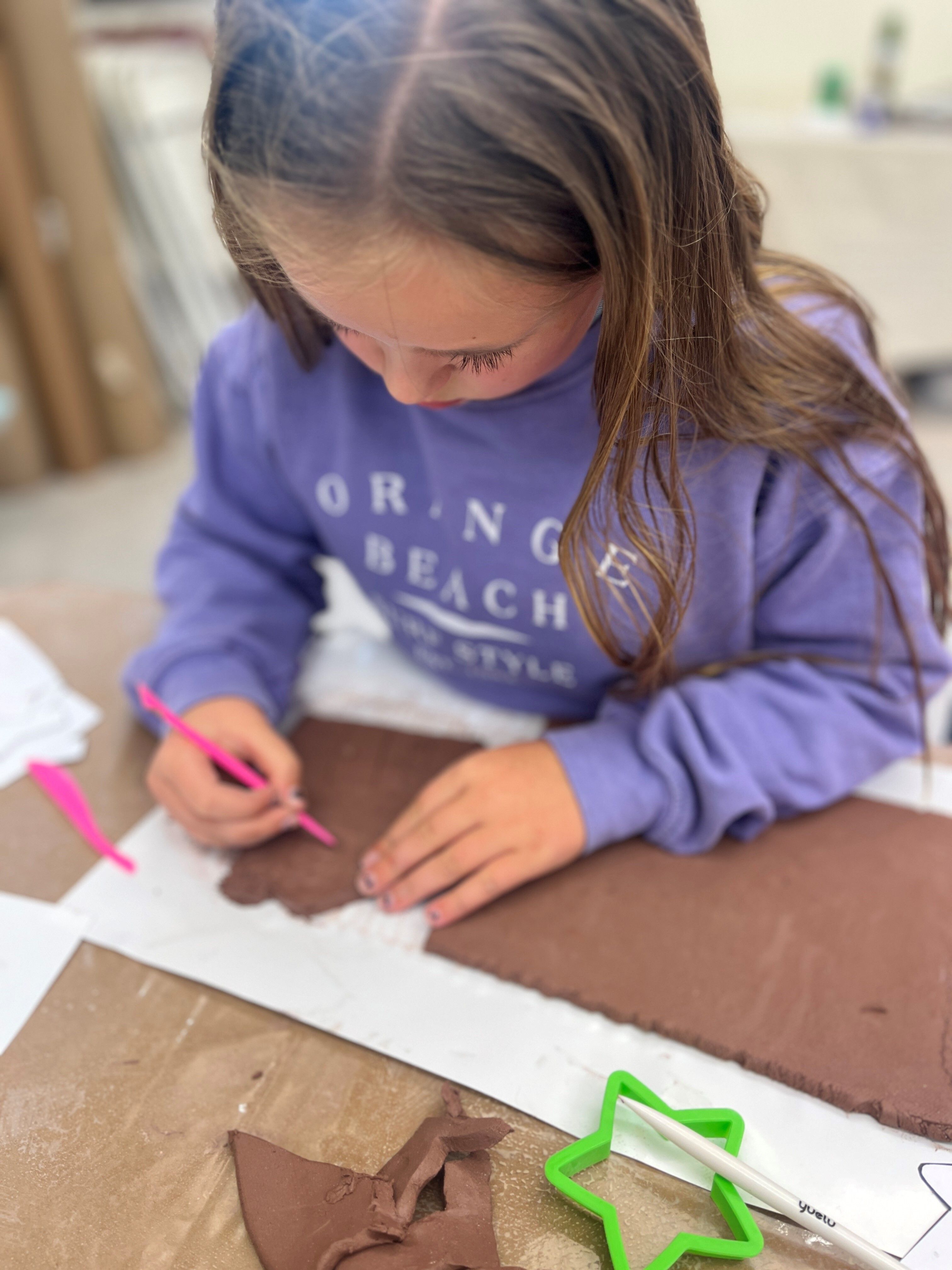 Girl making a clay slab carving