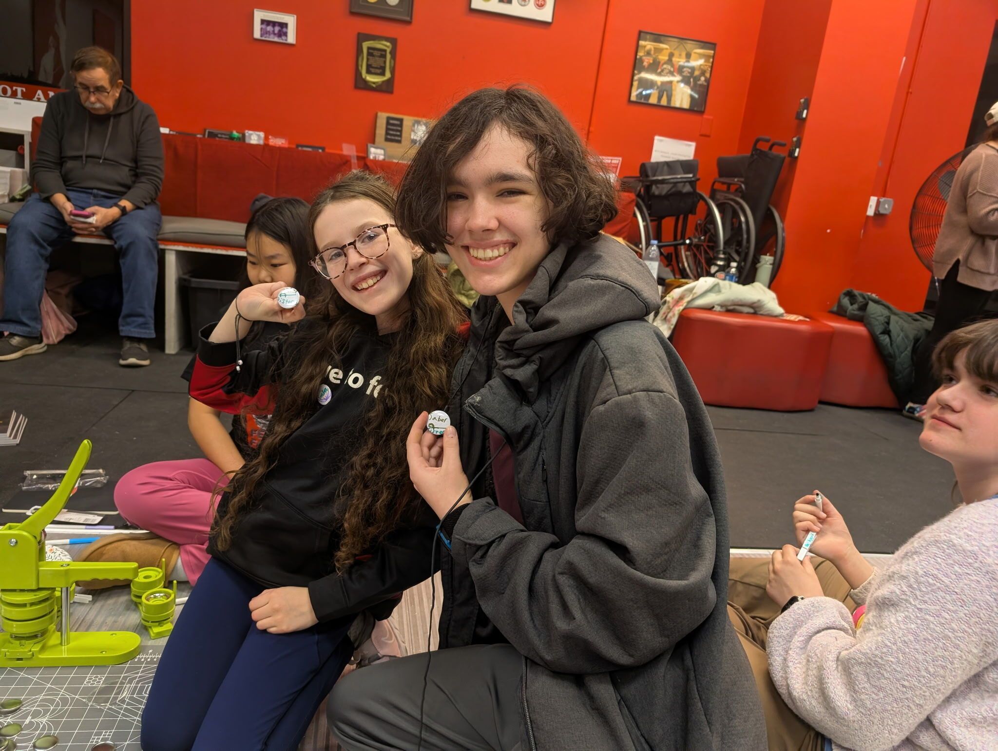 Two youth female fencers show off the pins they made