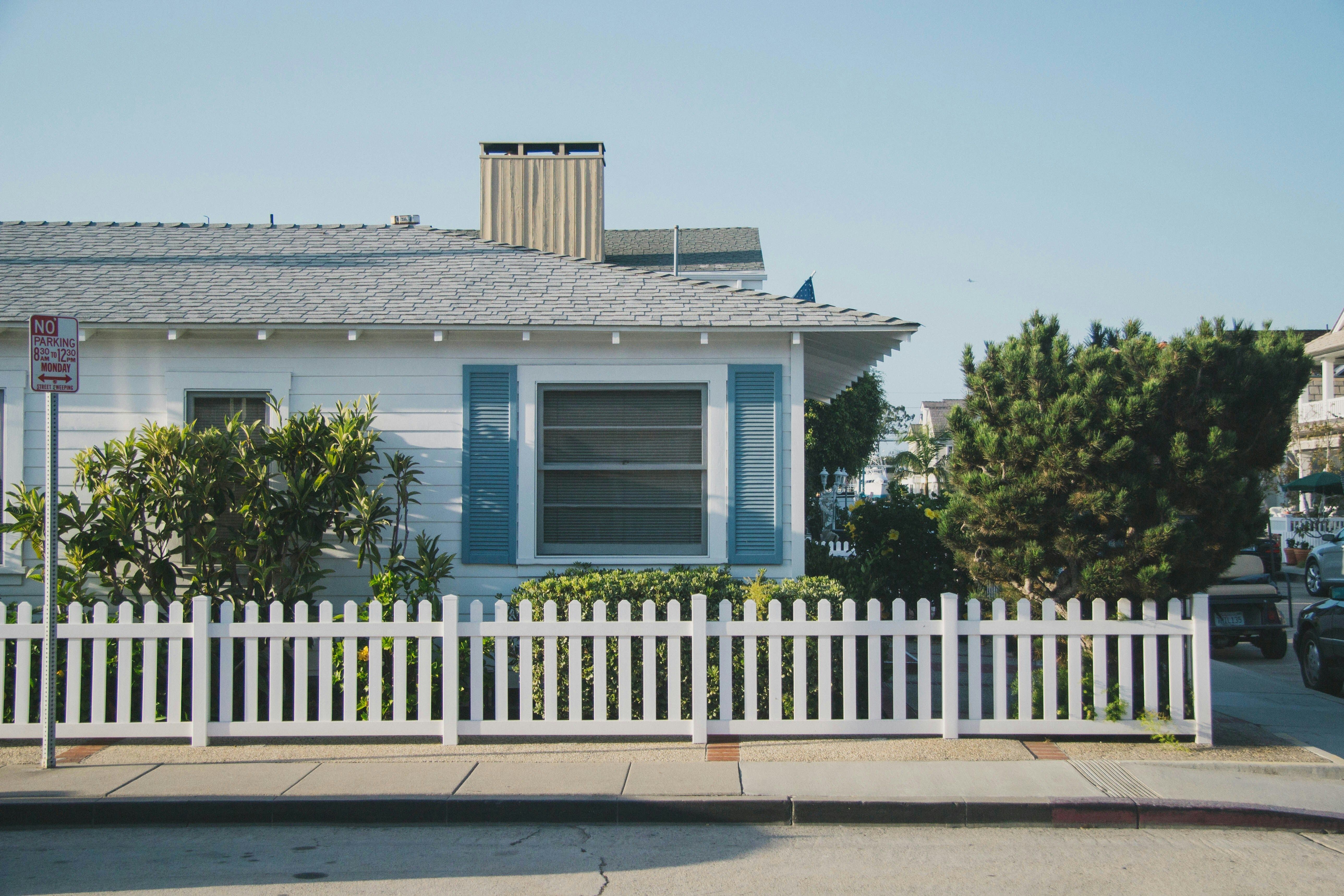 House exterior with shrubs and white picket fence.