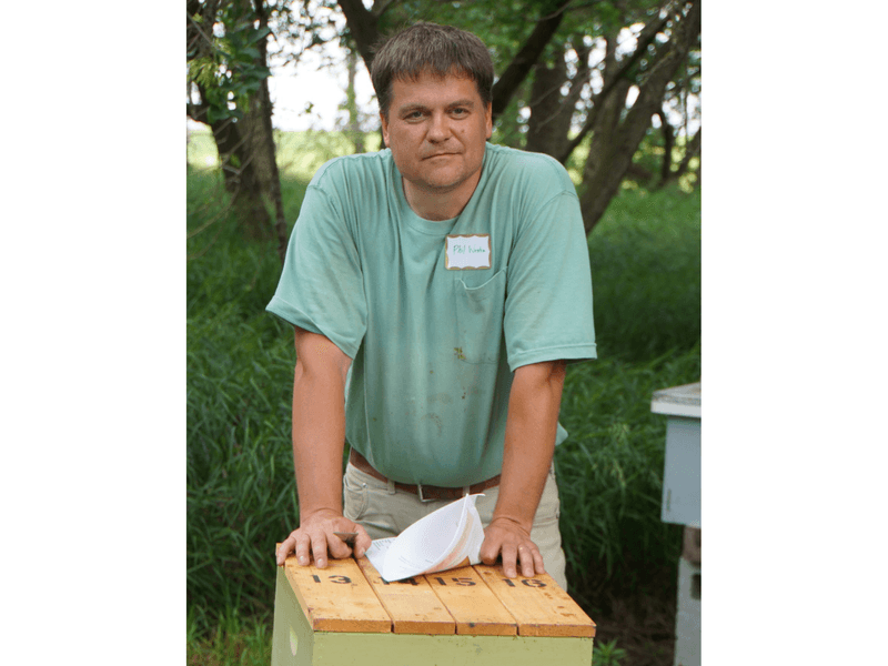 Photo of Phil Westra in front of bee hive