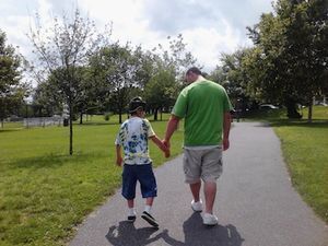 Coach walking with someone they support on a park sidewalk.