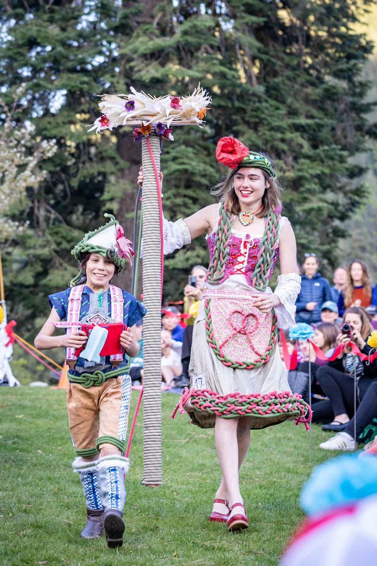 Picture of a woman and a young kid walking down the grass during a fashion show.