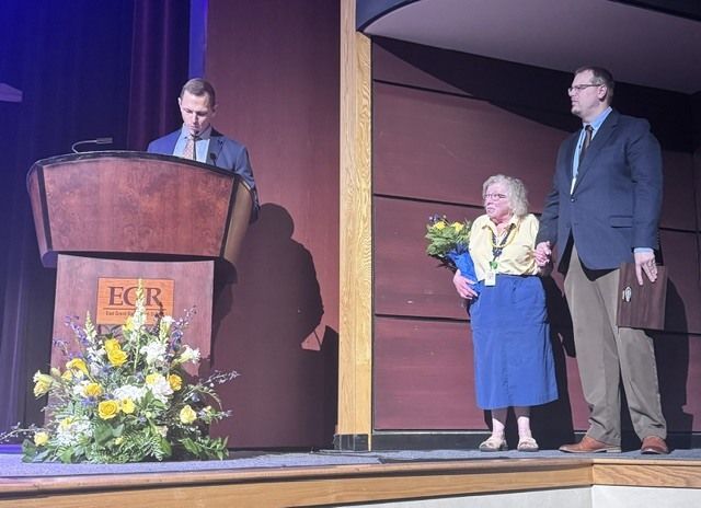Barbara Cone standing between EGRHS principal and assistant principal