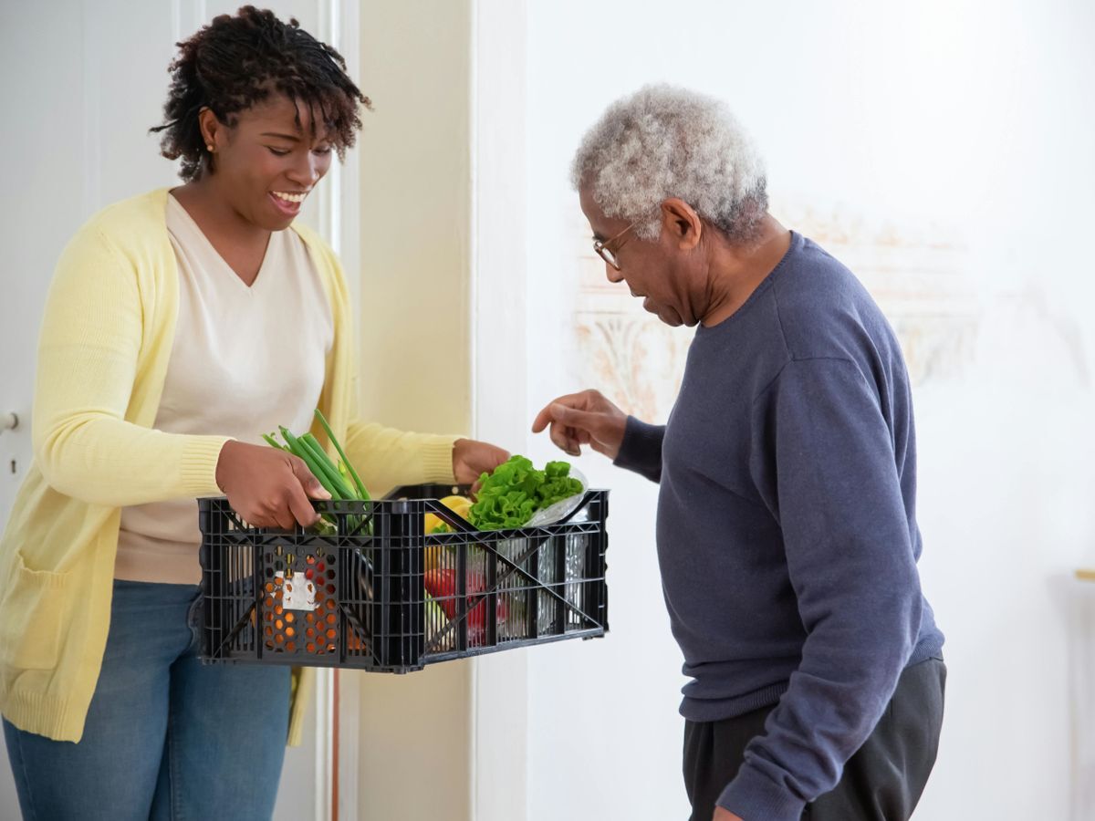 An older African American man receiving a food basket delivery