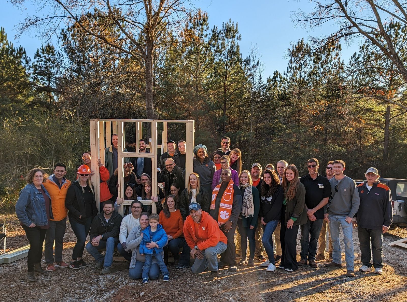 A group of people stand proudly in front of a playhouse under construction