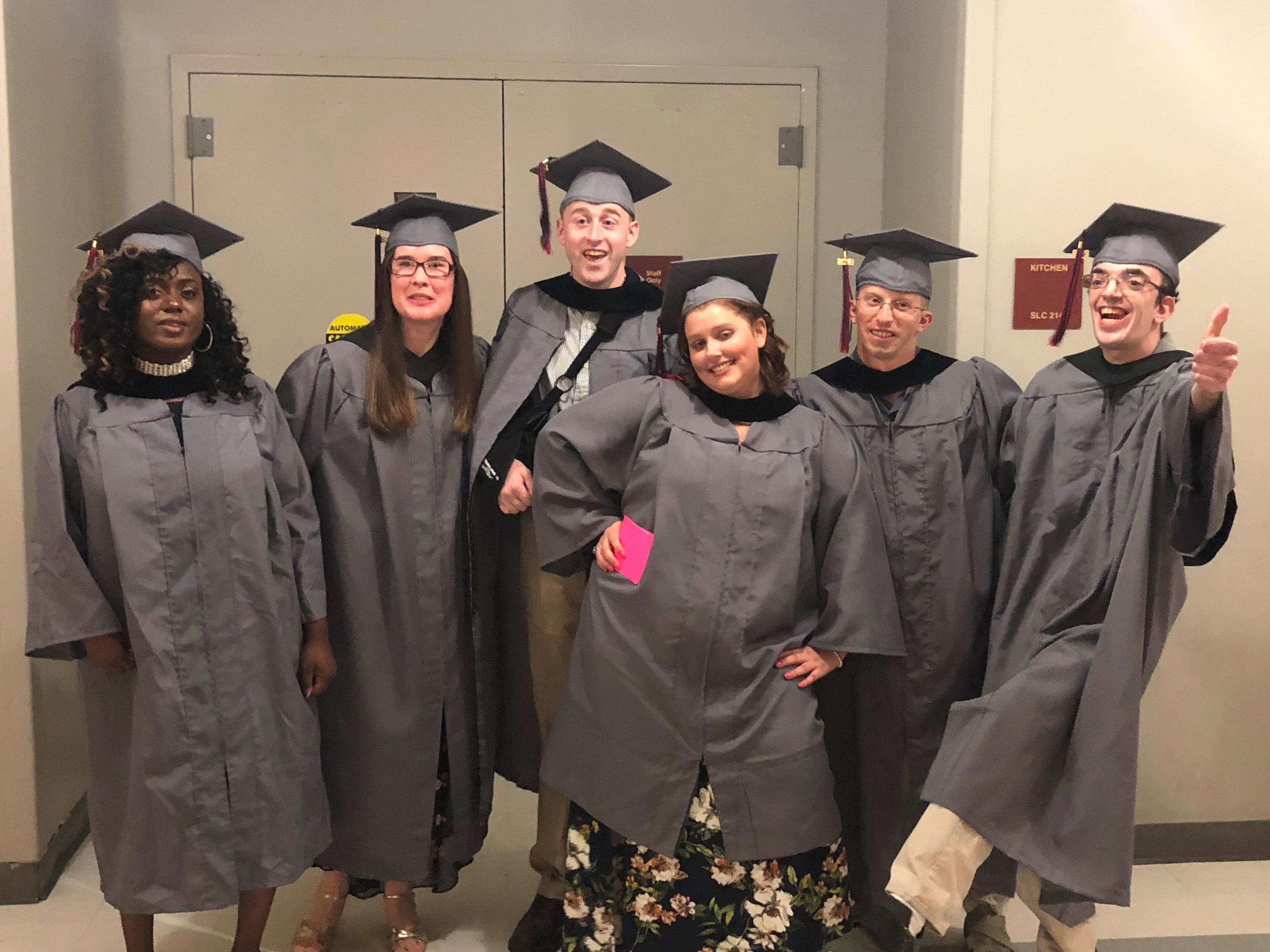 2019 Kach Graduates stand in cap and gown on graduation day.