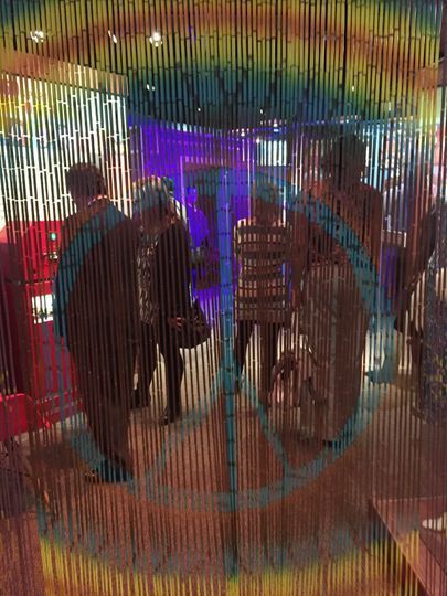 looking through a beaded curtain with a rainbow and peace sign at people in the Smoky Hill Museum's 1960 exhibit.