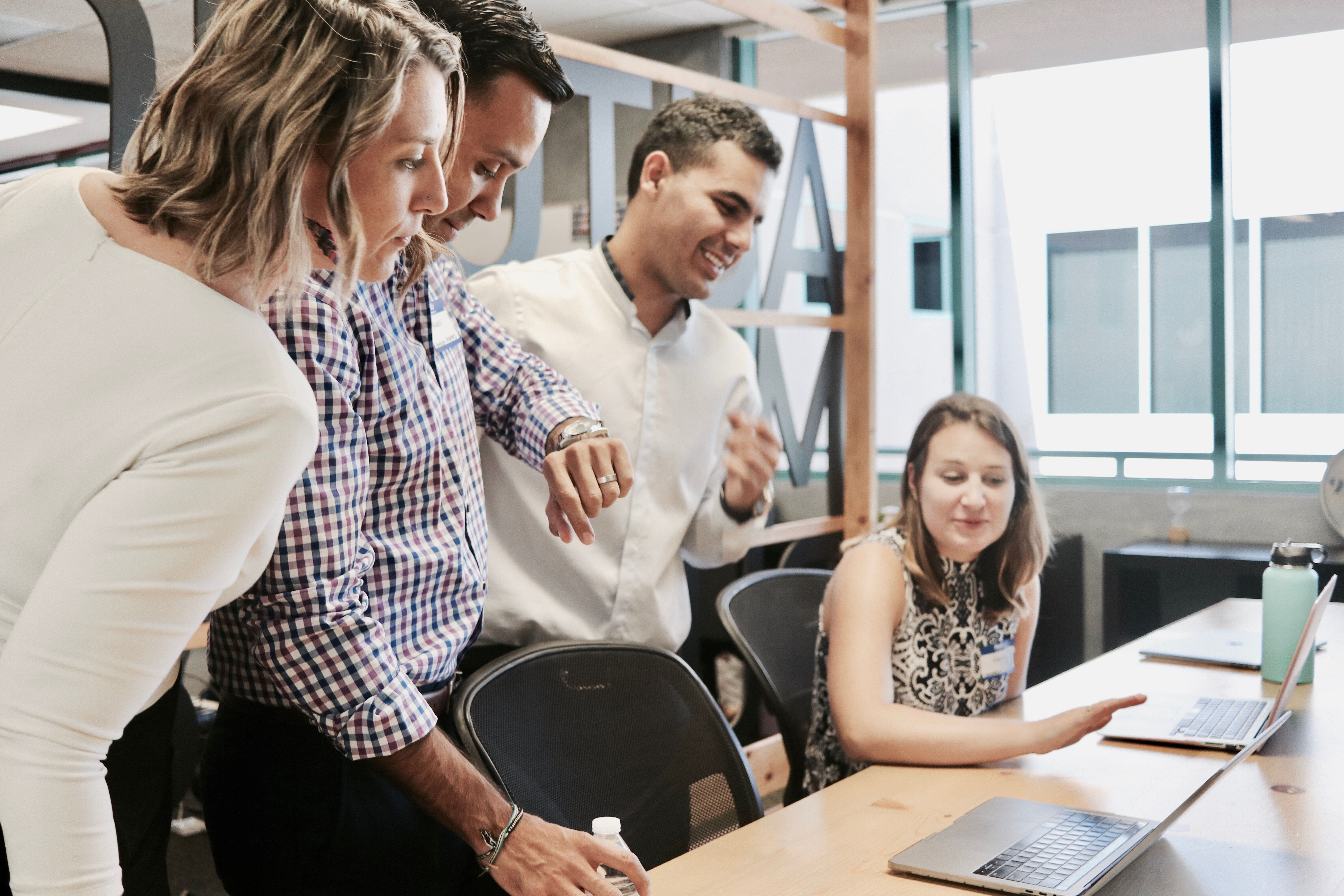 Four individuals meeting over two laptops