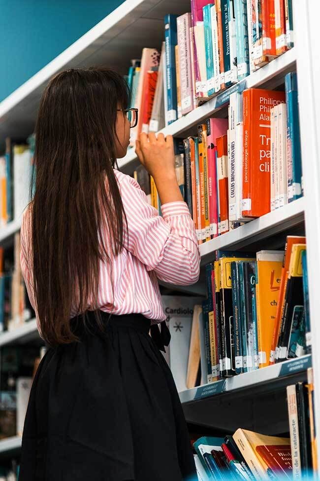 Person Looking at Library Books on Shelf (Medicine & Health)