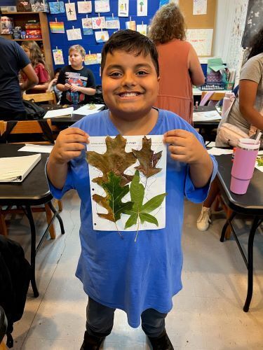 Picture of Henry smiling and holding artwork involving leaves.