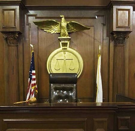 Federal Courtroom Interior – A modern courtroom with wood-paneled walls, courtroom furnishings, and a central seal mounted behind the bench, reflecting a formal and functional setting for judicial proceedings.