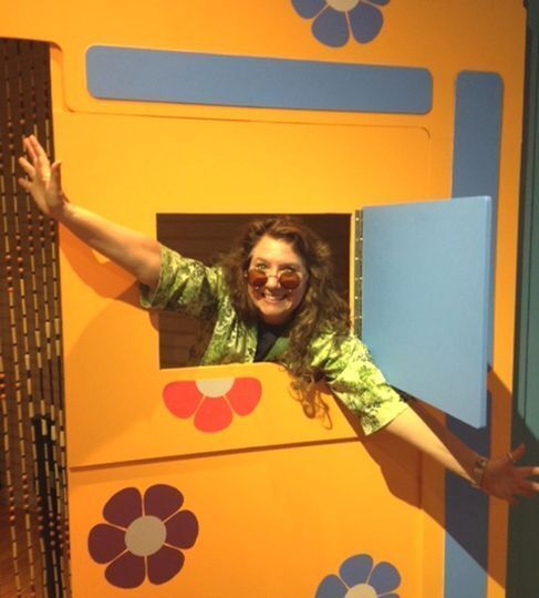 Woman sticking through a small door in a wall like the TV show "Laugh-In" in the Smoky Hill Museum's 1960 exhibit.