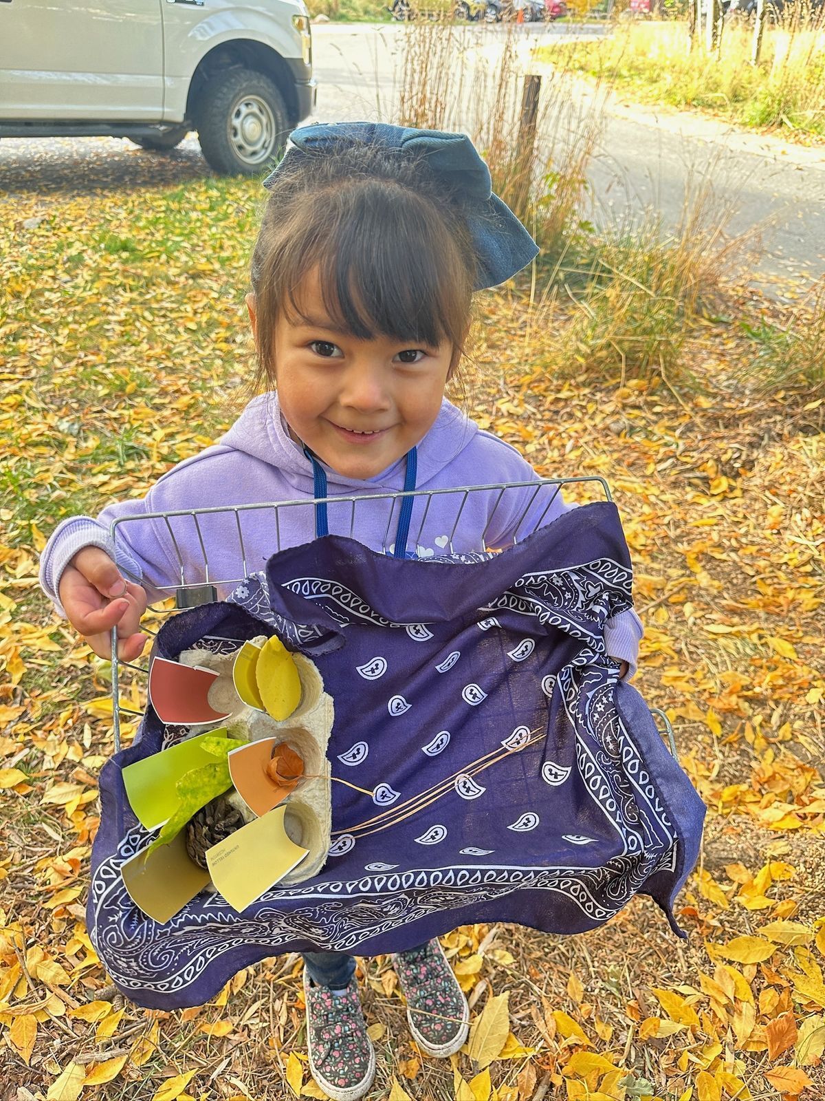 Young girl standing holding a basket standing on bright yellow-orange leaves.