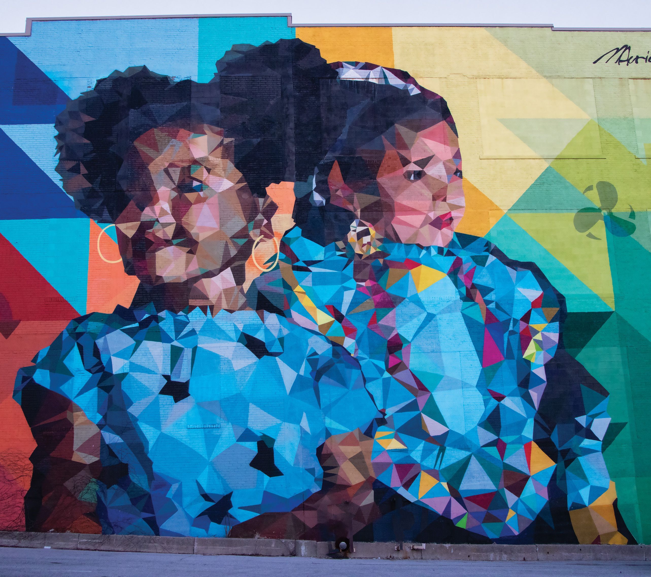 A geometrical mural by Mauricio Ramirez of two culturally diverse girls looking in opposite directions. The 5,0000-square-foot mural is on the side of Community Advocates building downtown Milwaukee. 