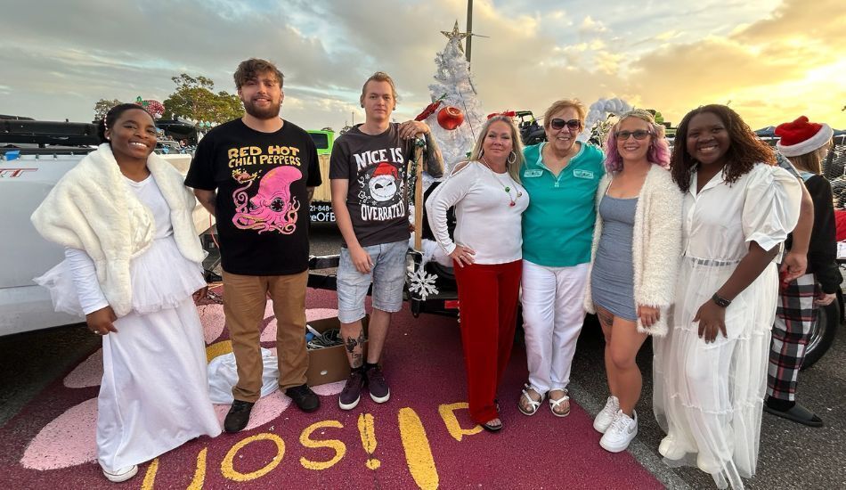 Photo of staff and partners at a holiday event, standing arm in arm and smiling.