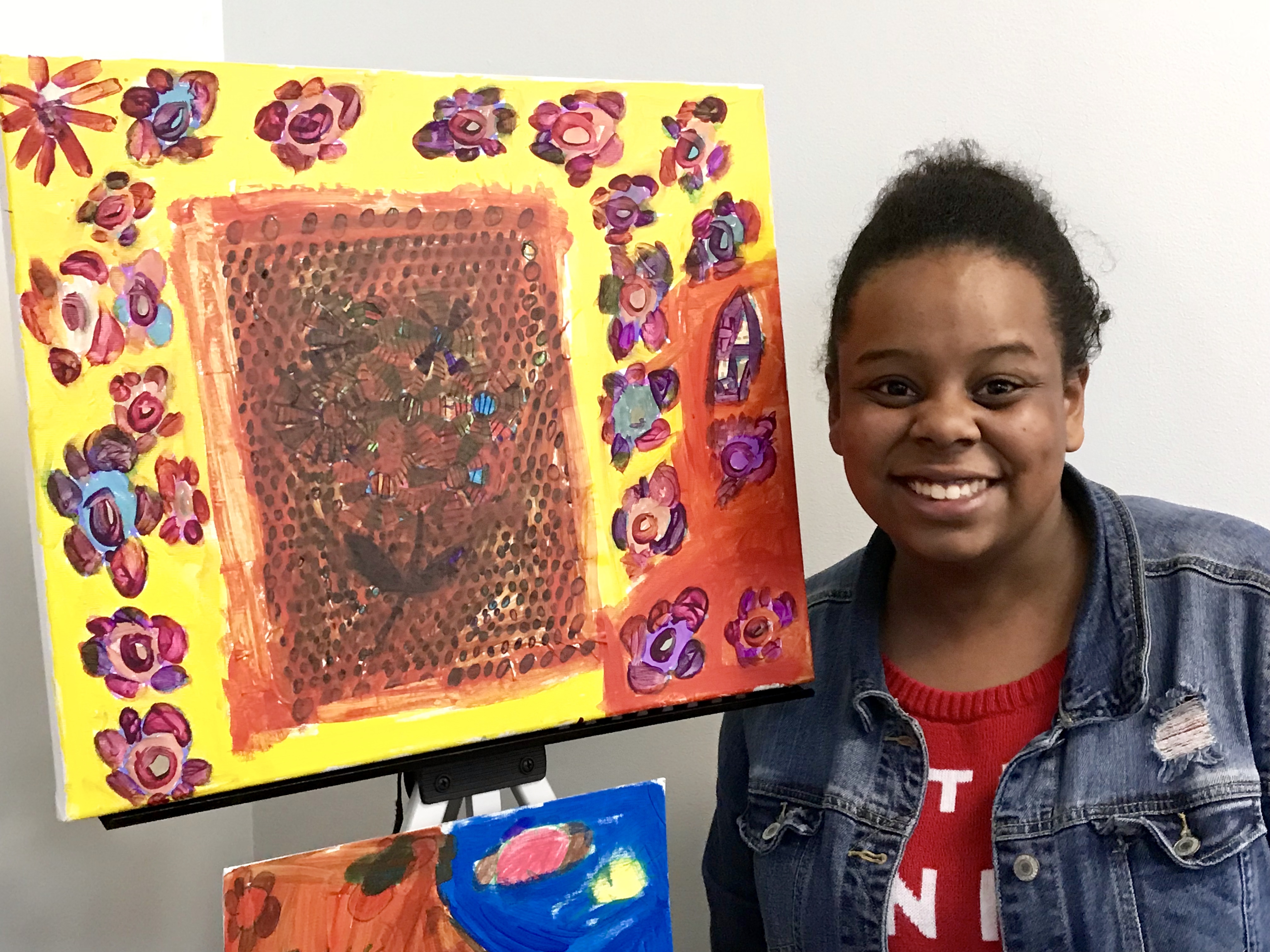 Cassie stands next to her original artwork on display during an exhibit