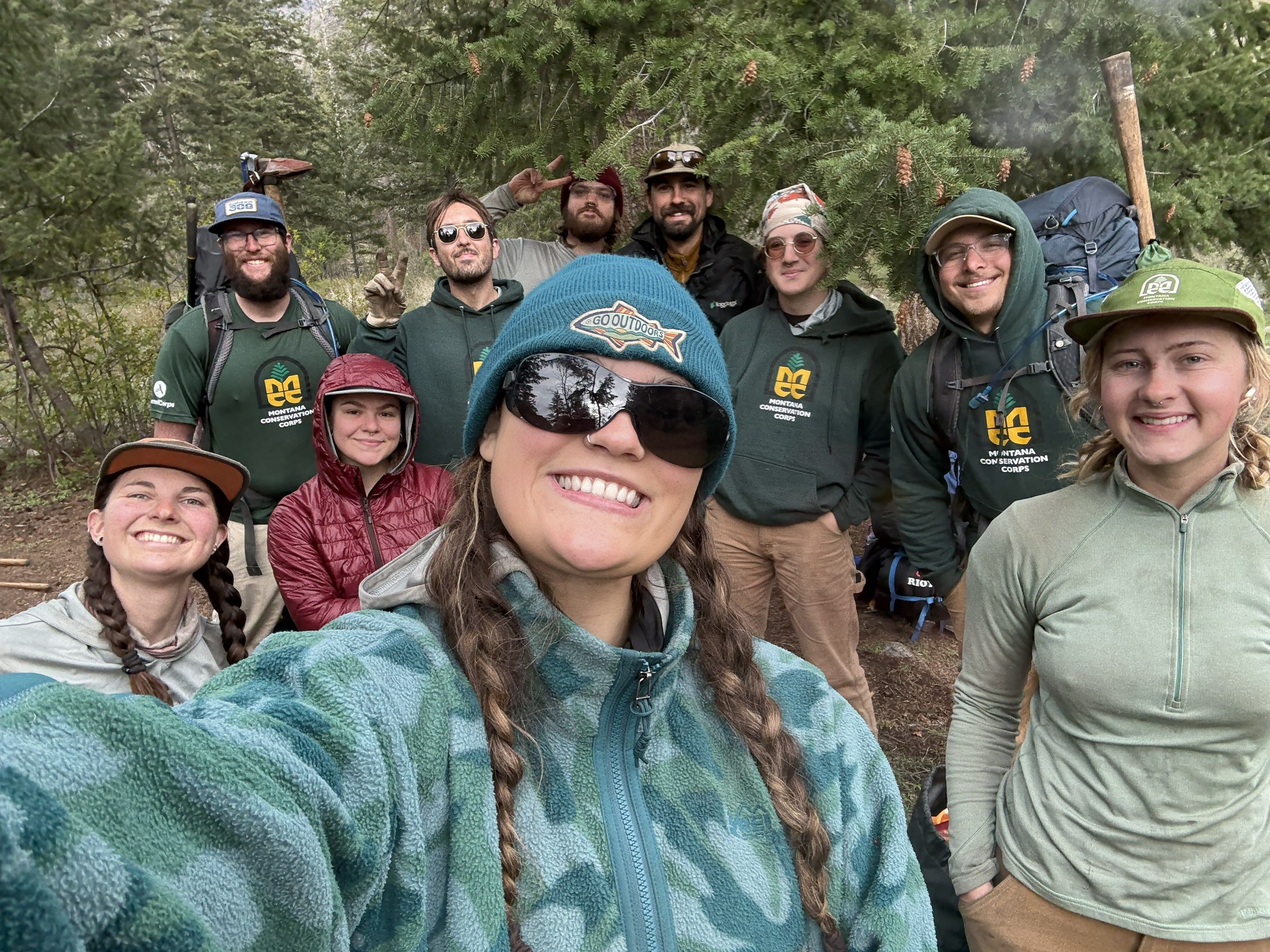 A selfie of the crew leaders against evergreen trees.