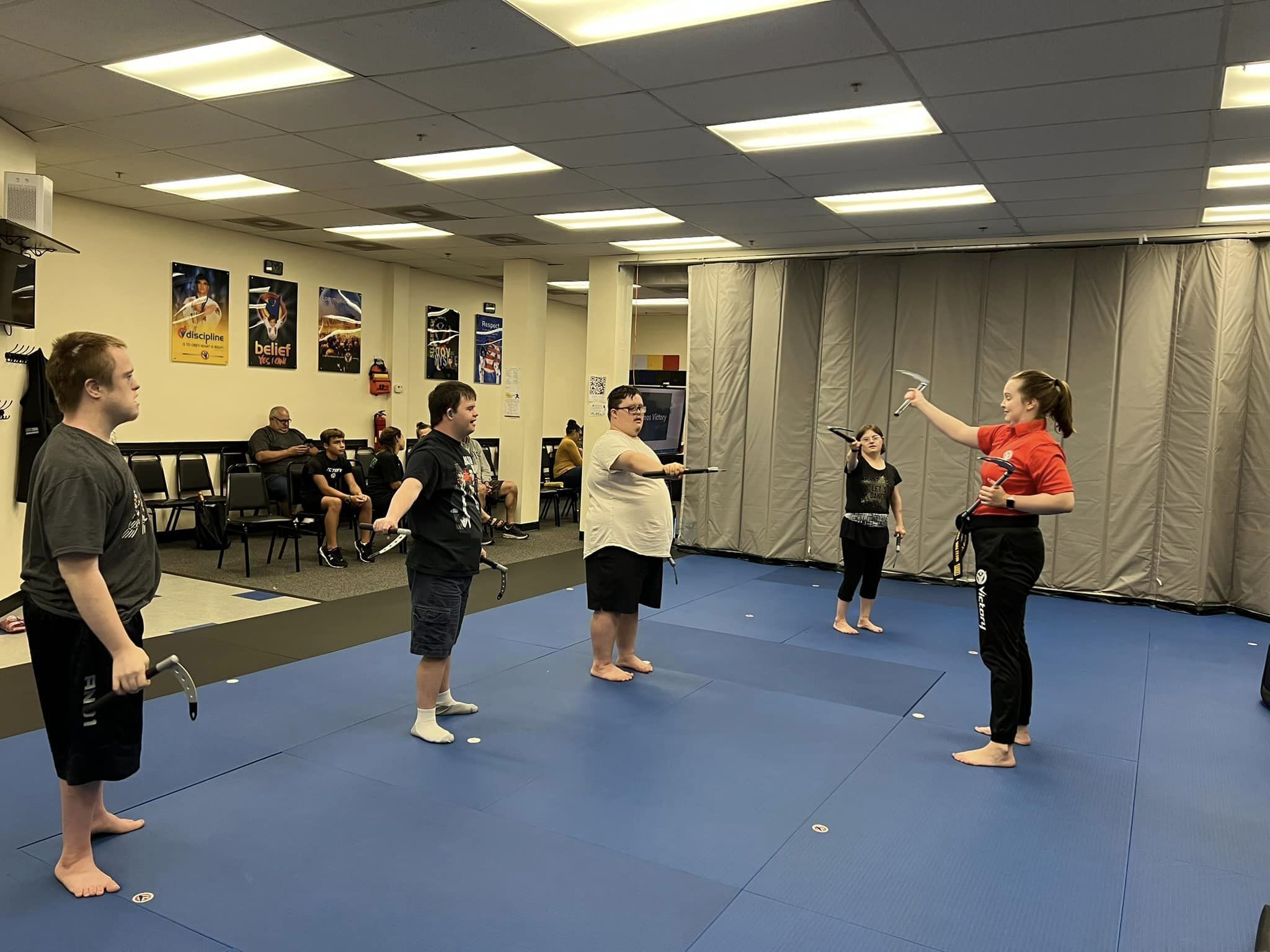 A karate instructor demonstrates a move for a group of karate class participants. The participants are adolescents and young adults with Down syndrome.