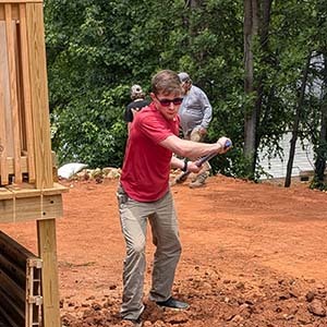 Two volunteers working on a paver walkway in red clay soil