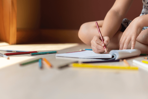 image of child drawing with colored pencils