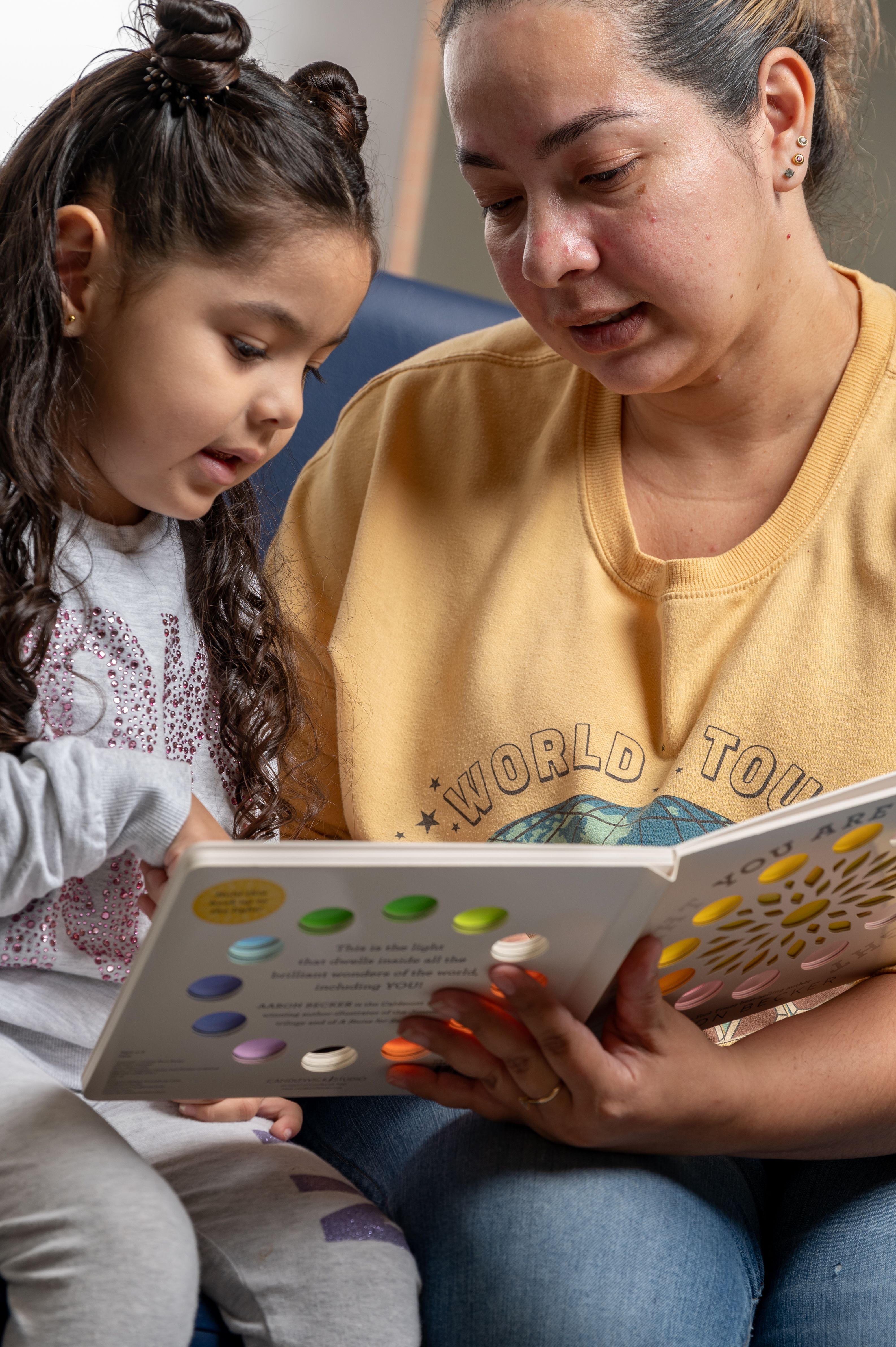 Mother and toddler daughter look down at book together