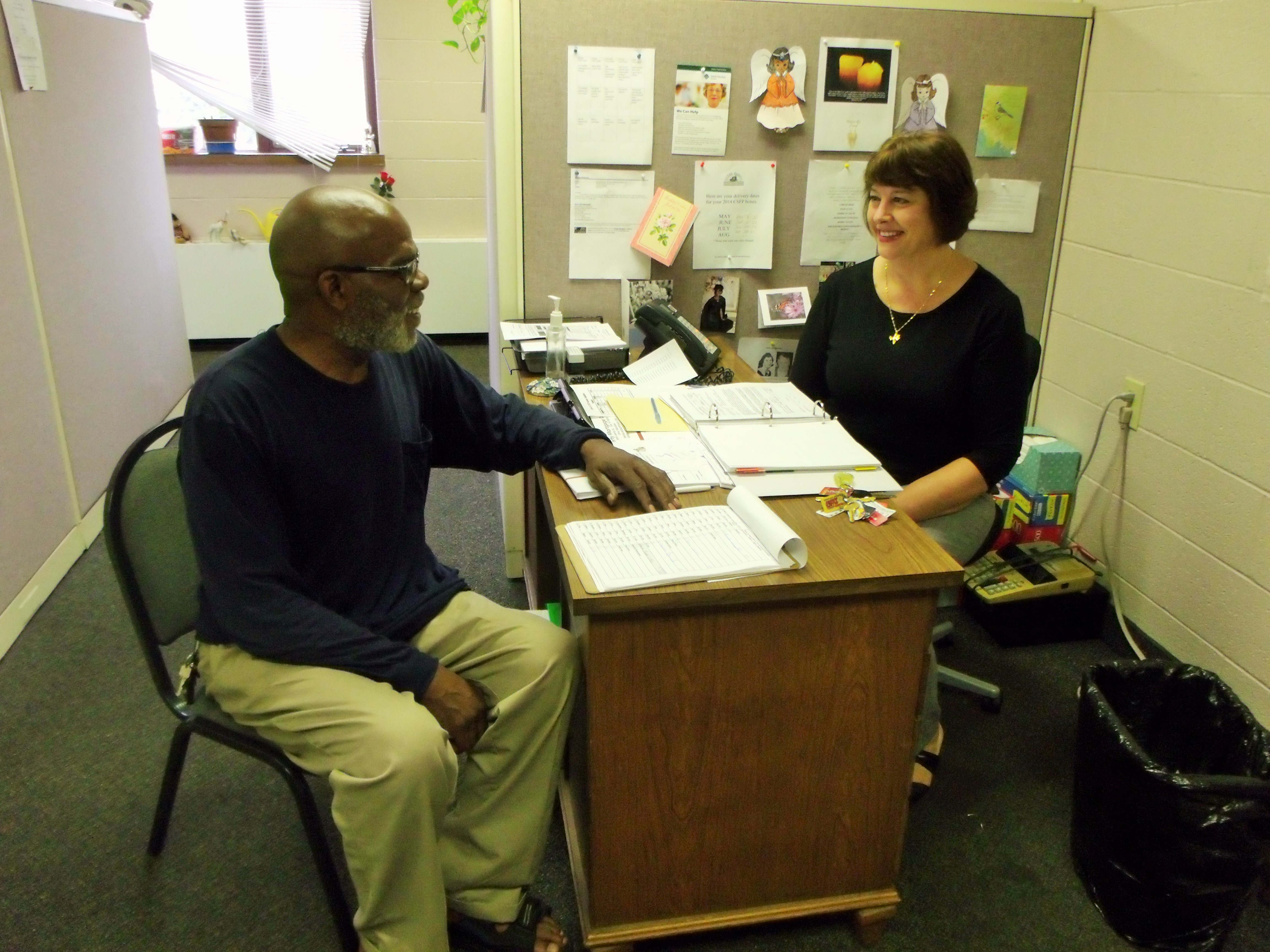A woman provides counseling to a man as they sit on opposite sides of a desk.