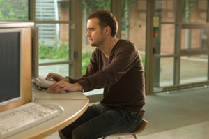 young man sitting at desk typing at computer