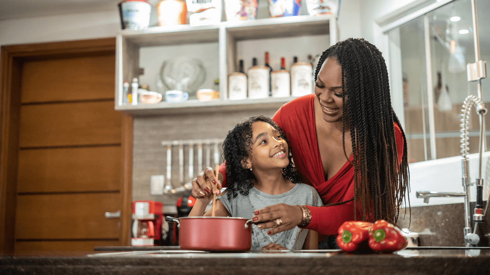 Mother and daughter cooking on electric stove