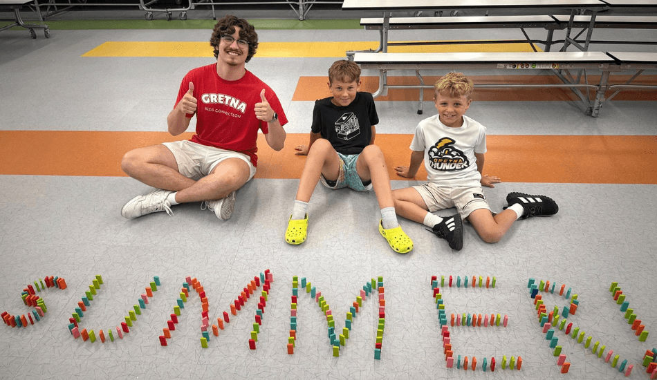 Kids Connection leader with students making a sign that says "Summer"
