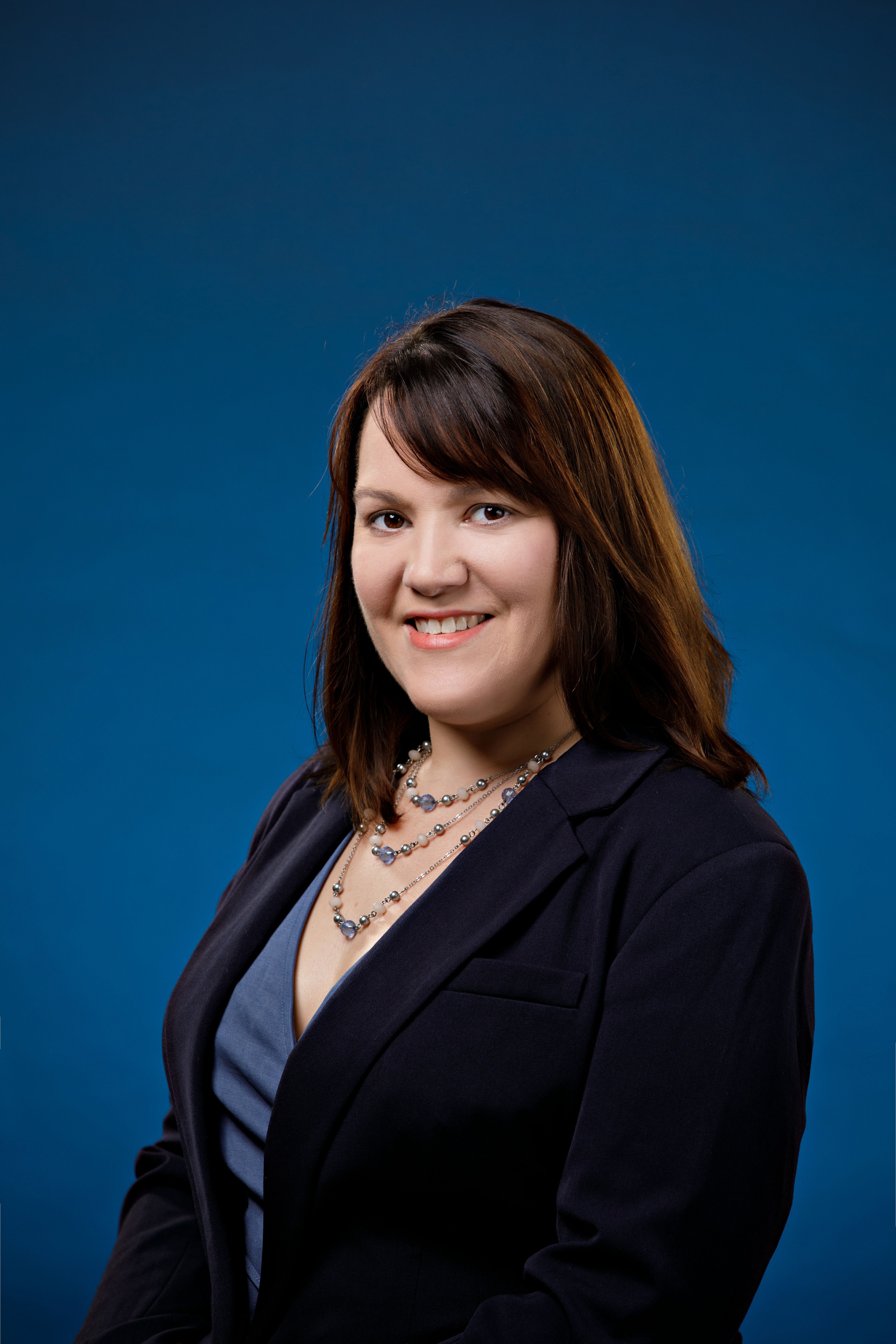Dr. Cheryl McFarland, a white woman with brown hair, is photographed smiling and wearing a black blazer and blue shirt.