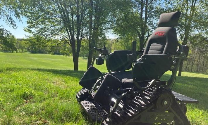 Track chair on a green grassy hill.