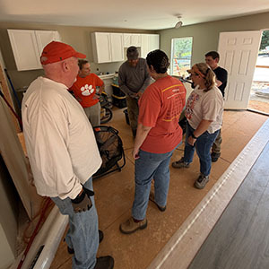 Group of volunteers standing together in a kitchen discussing the renovation project